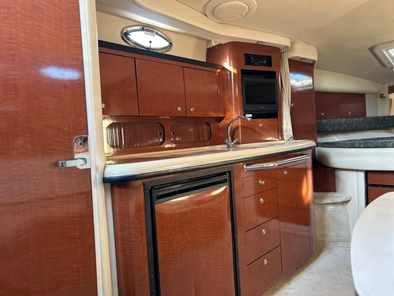 Slide: The Image of 2004 Sea Ray 340 Sundancer interior with wood cabinetry, sink, and compact kitchen area. - 15