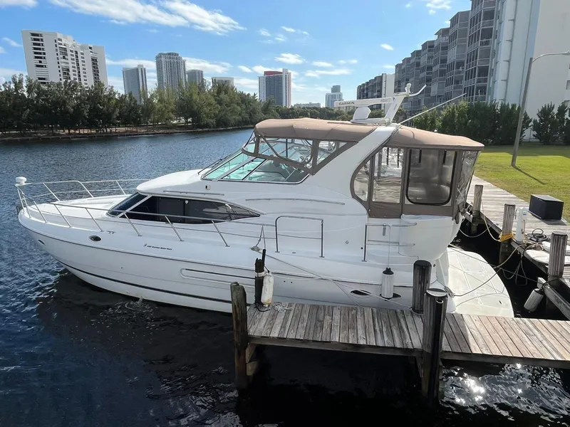 The Image of 2001 Cruisers Yachts 4450 Express Motoryacht docked by waterfront buildings. - 0
