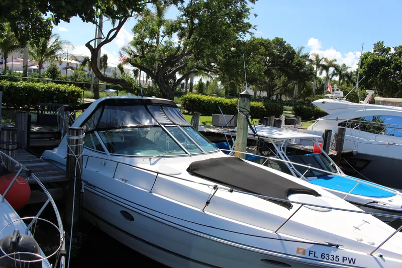 The Image of 2005 Cruisers Yachts 340 Express docked at a marina with lush greenery. - 0