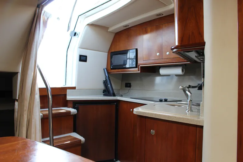 Slide: The Image of 2005 Cruisers Yachts 340 Express interior kitchen with wooden cabinets and modern appliances. - 12