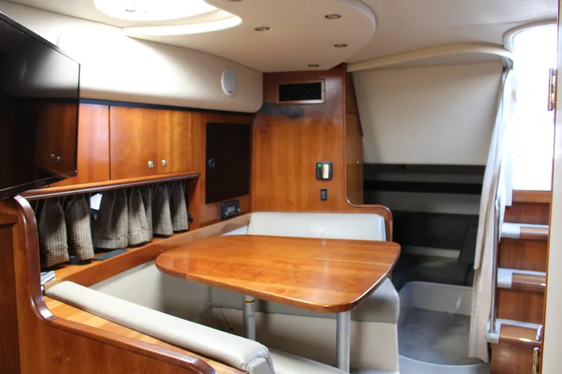 Slide: The Image of 2005 Cruisers Yachts 340 Express cabin interior with wooden dining table and seating. - 14
