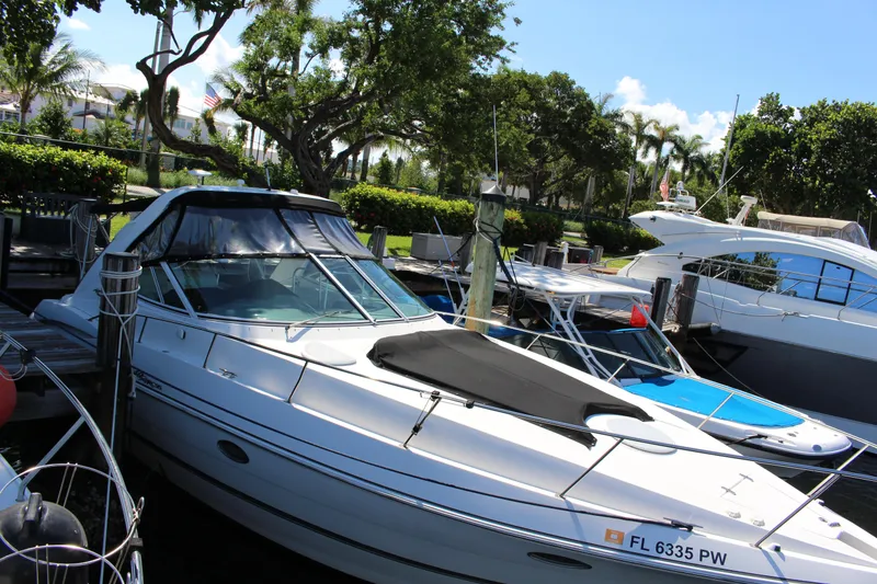 Slide: The Image of 2005 Cruisers Yachts 340 Express docked in a marina, surrounded by lush greenery. - 5