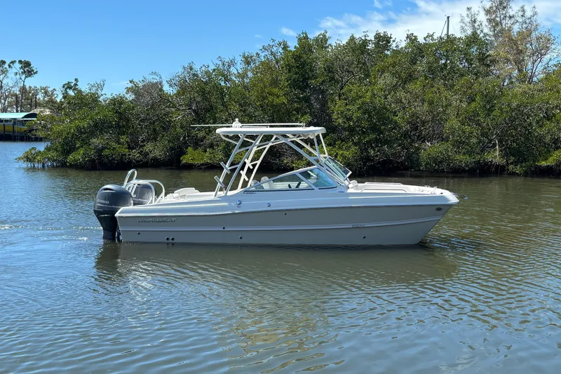 The Image of 2025 World Cat 230 SD boat on calm water, surrounded by lush greenery. - 0