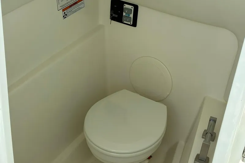 Slide: The Image of Interior of 2025 World Cat 230 SD boat featuring a compact marine toilet. - 10