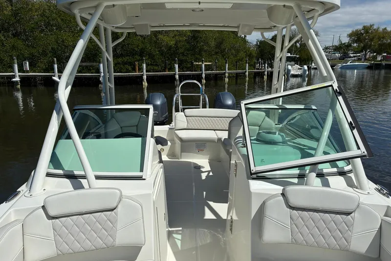 Slide: The Image of 2025 World Cat 230 SD boat interior with open windshield, docked near lush greenery. - 14