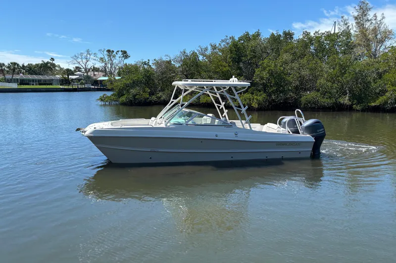Slide: The Image of 2025 World Cat 230 SD boat on calm water, surrounded by lush greenery. - 4