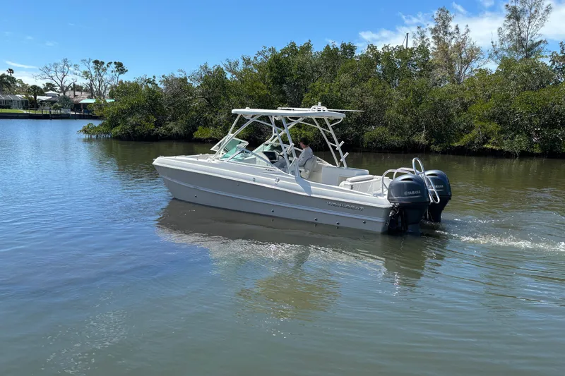 Slide: The Image of 2025 World Cat 230 SD boat cruising on a calm river with lush greenery. - 5