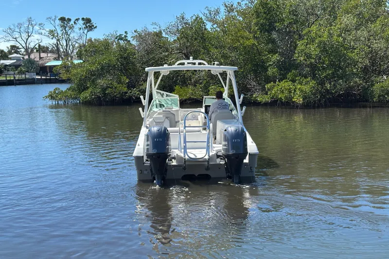 Slide: The Image of 2025 World Cat 230 SD boat navigating a calm river with lush greenery. - 6