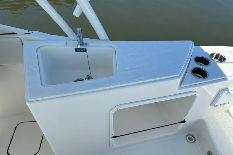 Slide: The Image of 2025 World Cat 230 SD boat sink and storage area with cup holders. - 8