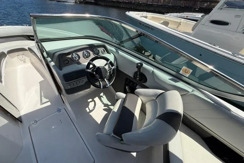 Slide: The Image of 2014 Regal 2500 Bowrider boat interior with steering wheel and dashboard, docked by the water. - 3
