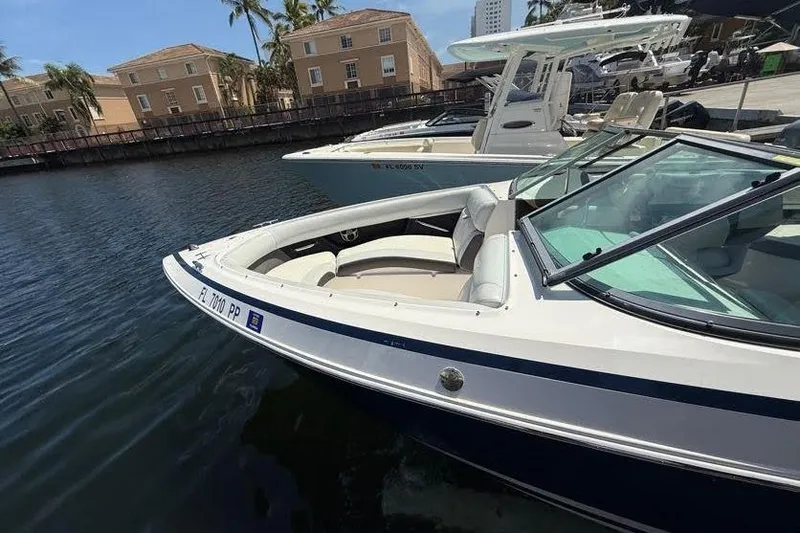 Slide: The Image of 2014 Regal 2500 Bowrider boat docked in marina, surrounded by buildings and palm trees. - 6