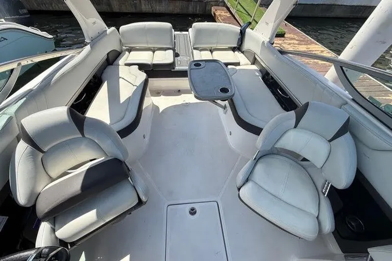 Slide: The Image of 2014 Regal 2500 Bowrider interior with white seating and table, docked by the water. - 7