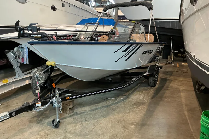 Slide: The Image of 2026 Starweld 16 SXT boat on trailer in showroom, featuring Minn Kota motor. - 7