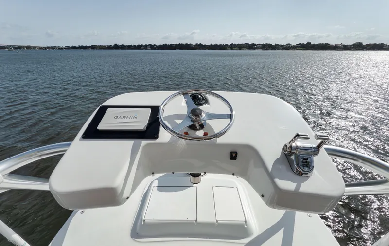 Slide: The Image of Helm of 2009 Hatteras 60GT yacht with steering wheel and controls, overlooking calm water. - 24