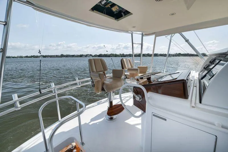 Slide: The Image of 2009 Hatteras 60GT yacht helm with leather seats overlooking calm waters. - 29