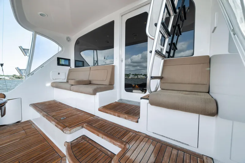 Slide: The Image of 2009 Hatteras 60GT yacht deck with cushioned seating and wooden steps. - 36