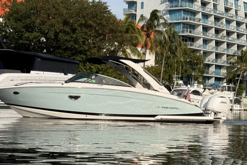 Slide: The Image of 2024 Regal LX9 boat docked near modern buildings and palm trees. - 6