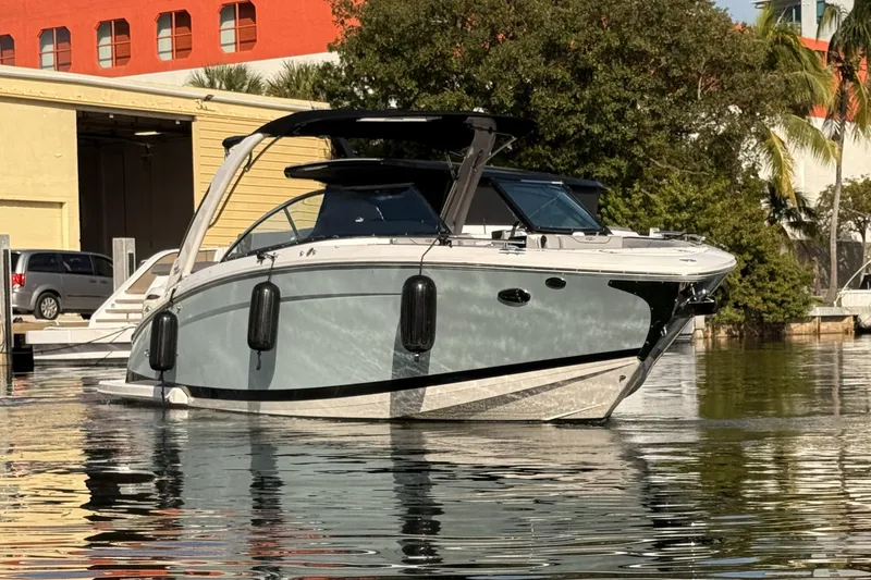 Slide: The Image of 2024 Regal LX9 boat docked on calm water, surrounded by trees and buildings. - 8