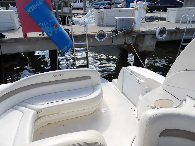 Slide: The Image of 2004 Sea Ray 320 Sundancer boat interior with white seating at a marina dock. - 24