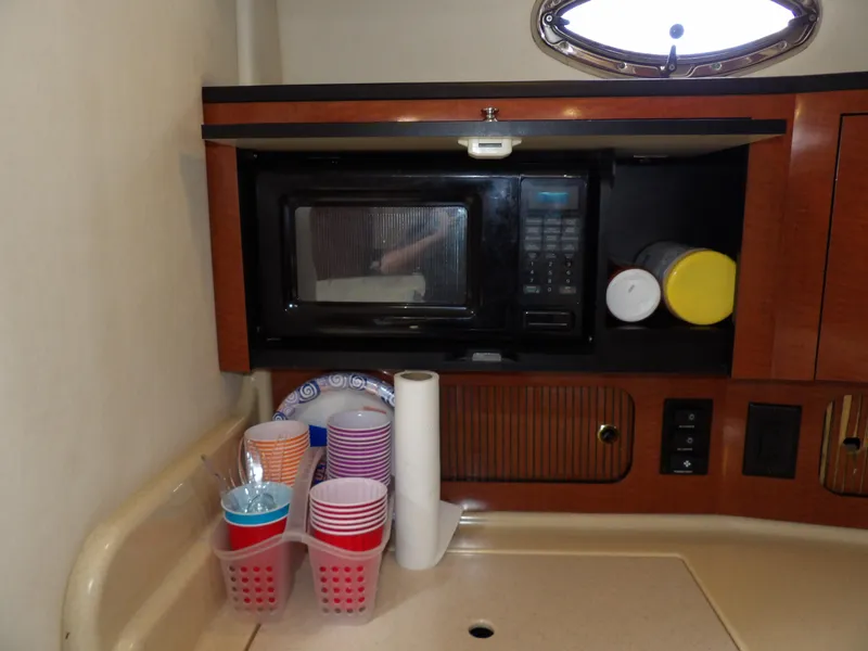 Slide: The Image of 2004 Sea Ray 320 Sundancer galley with microwave, cups, and storage. - 40