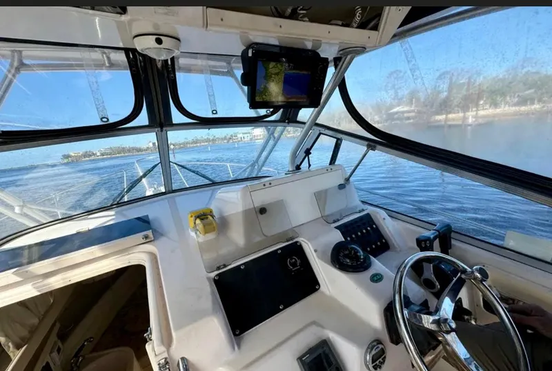 Slide: The Image of 2003 Grady-White Marlin 300 boat cockpit with steering wheel and navigation equipment, overlooking calm waters. - 13