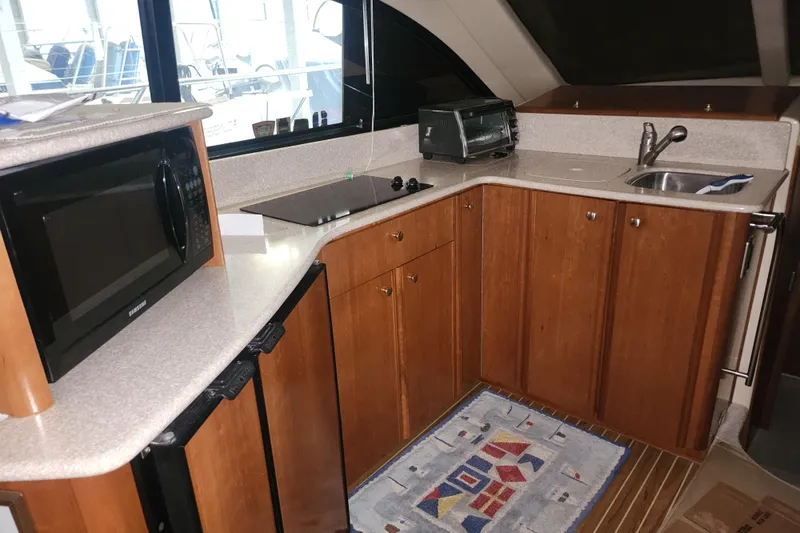 Slide: The Image of 2004 Meridian 411 Sedan yacht kitchen with microwave, stove, sink, and wooden cabinets. - 17