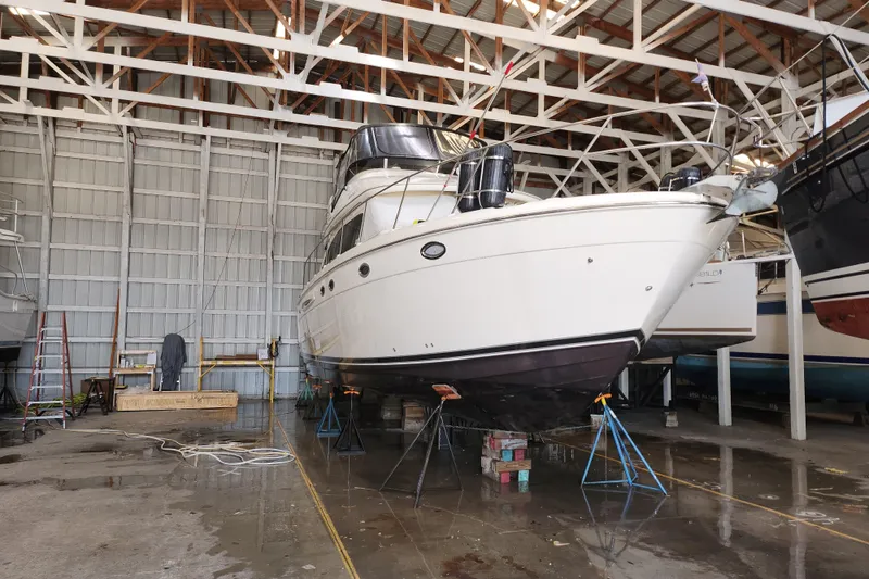Slide: The Image of 2004 Meridian 411 Sedan yacht in dry dock for maintenance inside a spacious boatyard. - 2