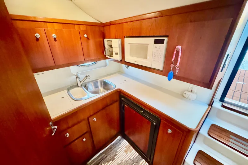 Slide: The Image of 2000 Tiara 37 Open yacht kitchen with wood cabinets, sink, and microwave. - 23