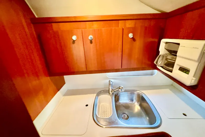 Slide: The Image of Compact kitchen area in a 2000 Tiara 37 Open boat with sink and coffee maker. - 24