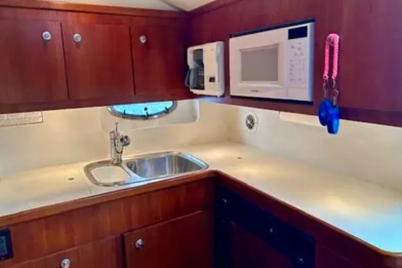 Slide: The Image of 2000 Tiara 37 Open yacht kitchen with sink, microwave, and wooden cabinets. - 29