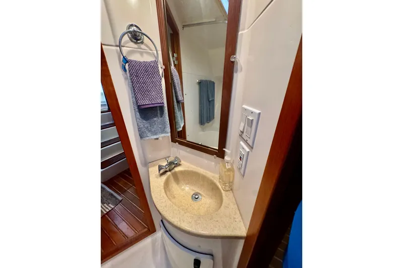 Slide: The Image of Bathroom sink area in a 2000 Tiara 37 Open yacht, featuring a mirror and towel rack. - 49