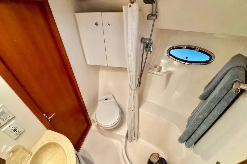 Slide: The Image of Bathroom interior of 2000 Tiara 37 Open yacht, featuring shower, toilet, and porthole window. - 52