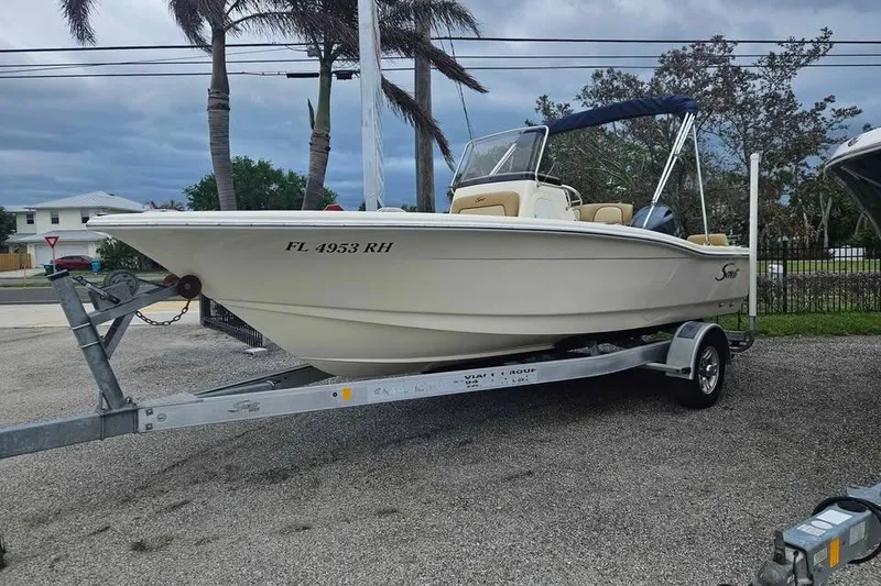 Slide: The Image of 2017 Scout 195 Sportfish boat on trailer, parked outdoors with palm trees in background. - 3