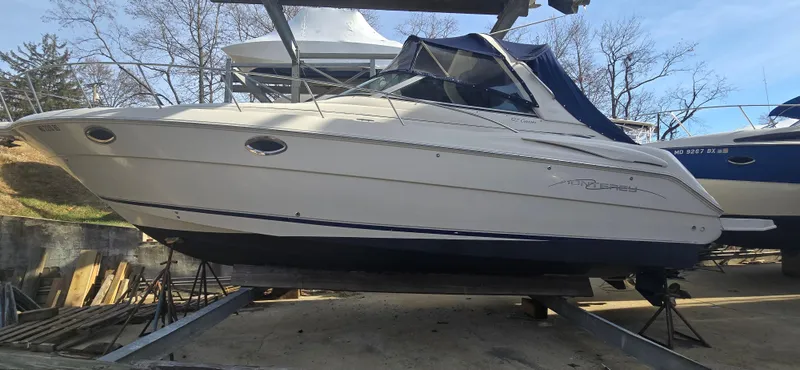 The Image of 2002 Monterey 322 Cruiser boat on dry dock, side view with blue canopy. - 0