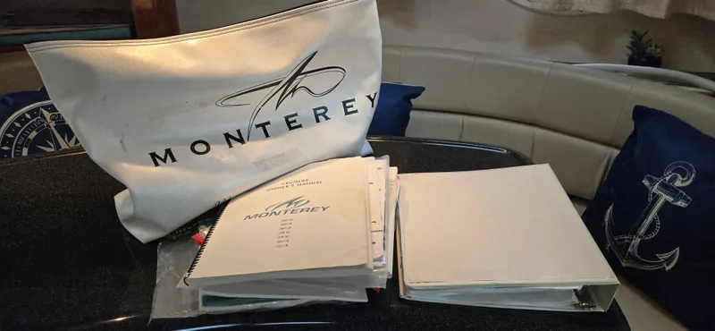 Slide: The Image of Monterey 322 Cruiser 2002 manuals and bag on boat interior table. - 17