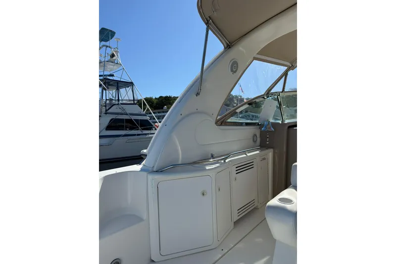 Slide: The Image of 2000 Sea Ray 410 Express Cruiser interior with cabinetry and seating, docked under clear skies. - 15