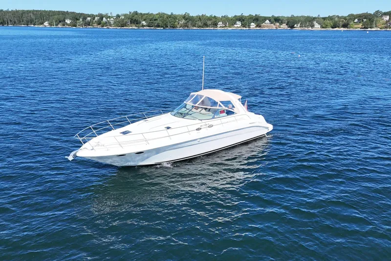 Slide: The Image of 2000 Sea Ray 410 Express Cruiser on calm blue water, scenic shoreline background. - 3