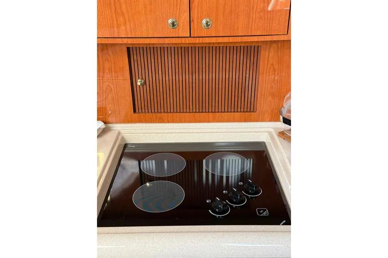 Slide: The Image of Stovetop in 2000 Sea Ray 410 Express Cruiser kitchen with wooden cabinetry. - 49
