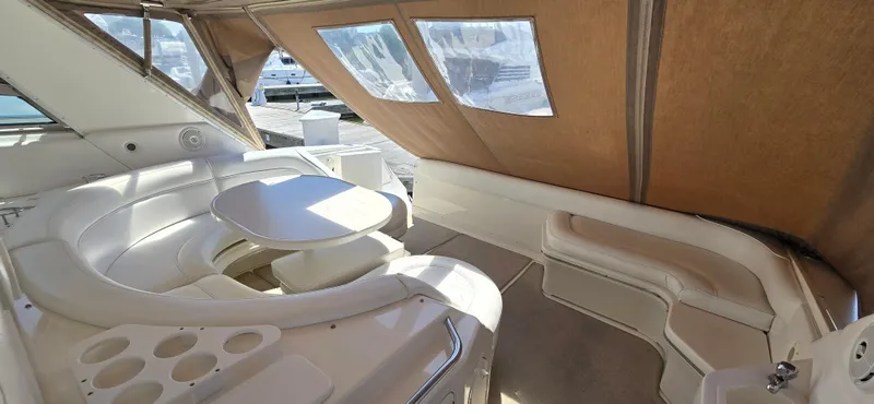 Slide: The Image of 1999 Sea Ray 50 Sundancer interior with white seating and table, enclosed by tan canopy. - 10