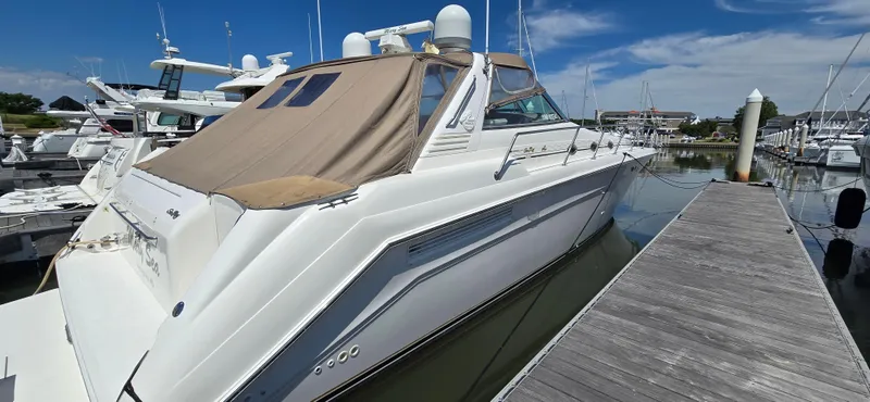 Slide: The Image of 1999 Sea Ray 50 Sundancer yacht docked at marina under clear blue sky. - 5