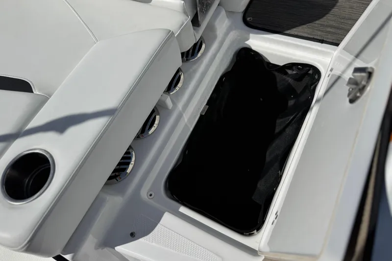 Slide: The Image of 2023 Four Winns HD3 boat storage compartment with cup holder and seating area. - 11