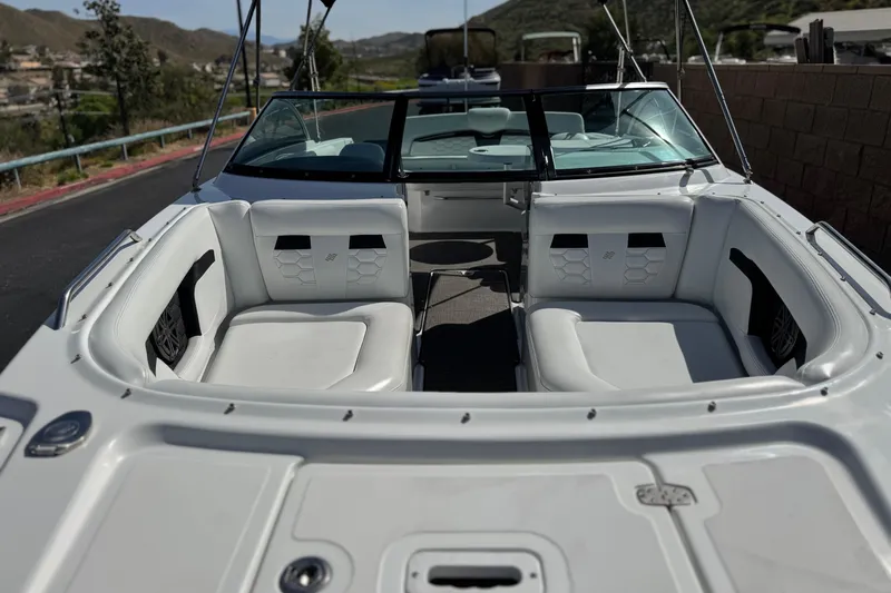 Slide: The Image of 2023 Four Winns HD3 boat interior with white seating and windshield, parked outdoors. - 14