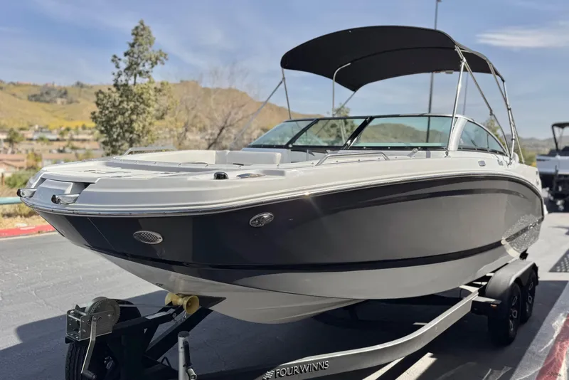 Slide: The Image of 2023 Four Winns HD3 boat on trailer, parked outdoors with scenic background. - 3