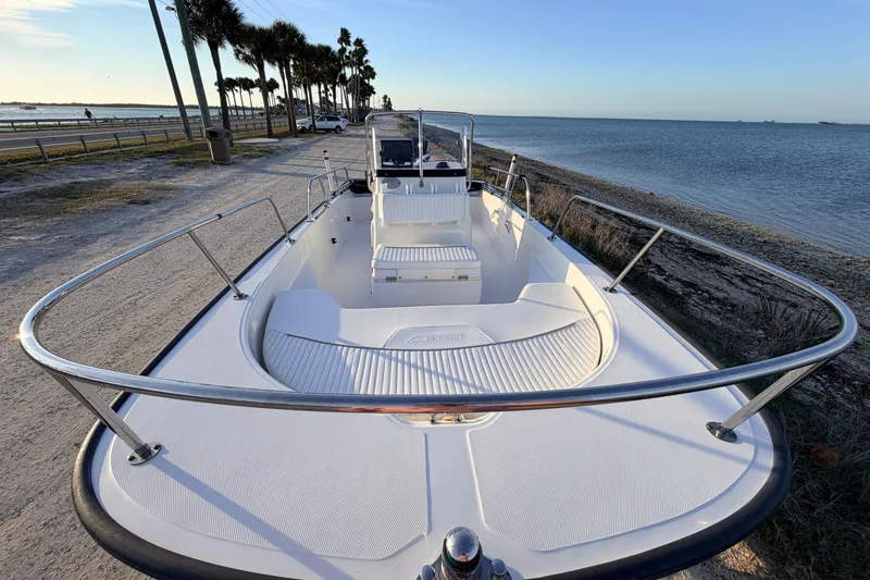 Slide: The Image of 2010 Boston Whaler 170 Montauk boat docked by the seaside, showcasing spacious deck and seating. - 16