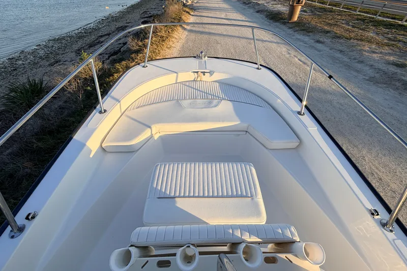Slide: The Image of 2010 Boston Whaler 170 Montauk boat interior, featuring cushioned seating and railings by the water. - 21
