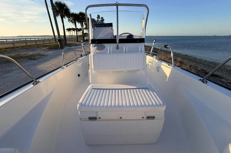 Slide: The Image of 2010 Boston Whaler 170 Montauk boat interior with seating, near a scenic shoreline. - 26