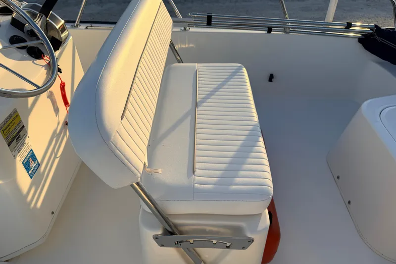 Slide: The Image of 2010 Boston Whaler 170 Montauk boat interior with white cushioned seating and steering wheel. - 42