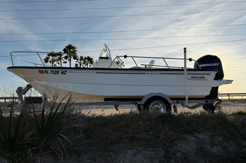 Slide: The Image of 2010 Boston Whaler 170 Montauk boat on trailer, parked outdoors with palm trees in background. - 5