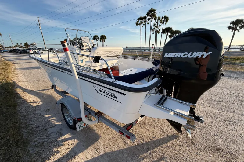 Slide: The Image of 2010 Boston Whaler 170 Montauk boat with Mercury engine on trailer, parked near palm trees. - 6