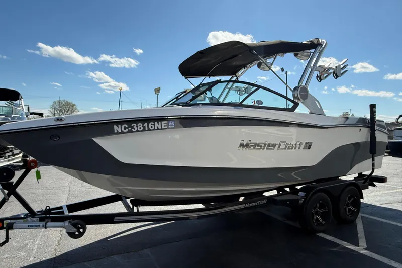The Image of 2023 MasterCraft XT22 boat on trailer under clear blue sky. - 0